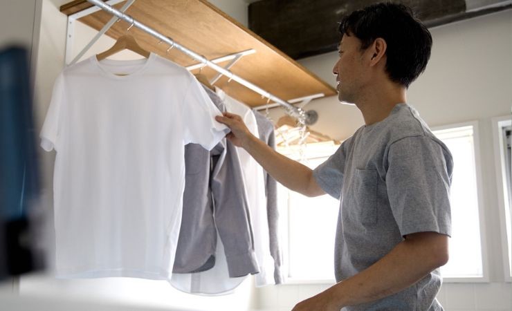 una persona che prende i vestiti dalla grucce