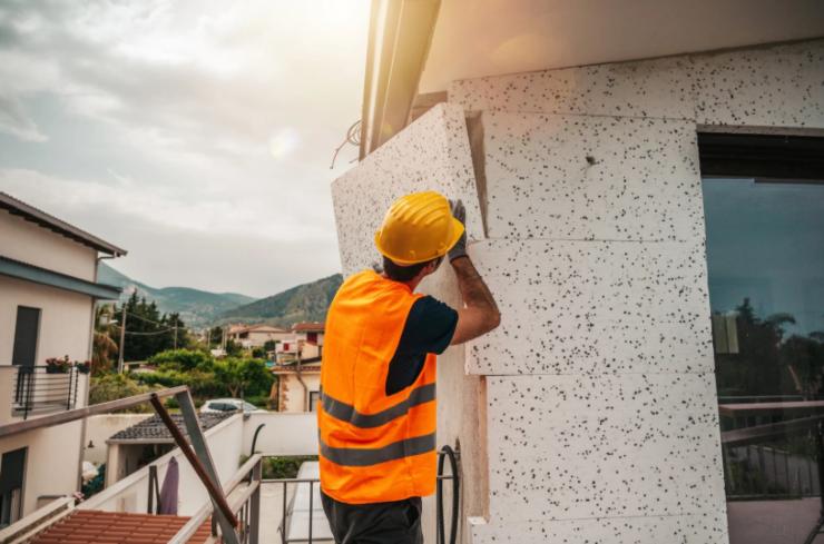 operaio che installa il cappotto termico su una casa
