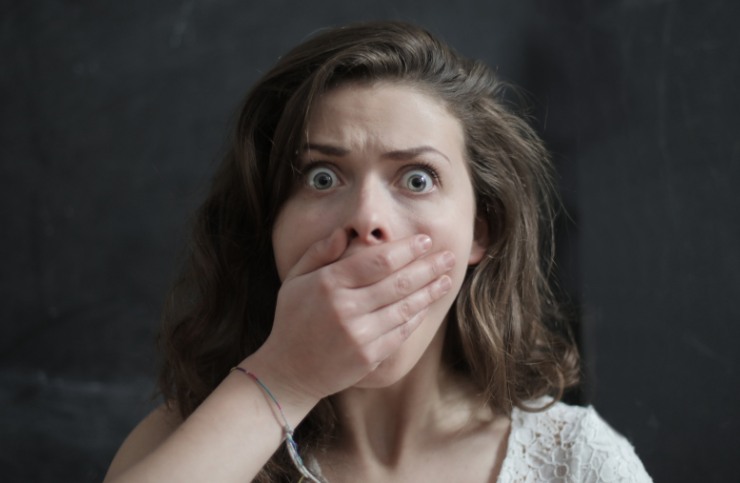 donna scioccata con una mano davanti alla bocca